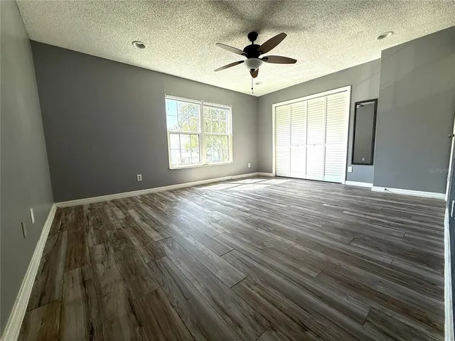 a view of an empty room with a window and wooden floor