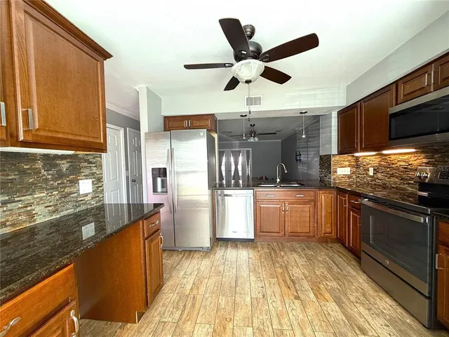 a kitchen with stainless steel appliances kitchen island granite countertop a refrigerator a stove and a sink