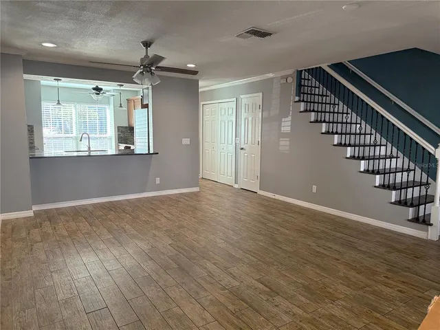 a view of an empty room with wooden floor and staircase