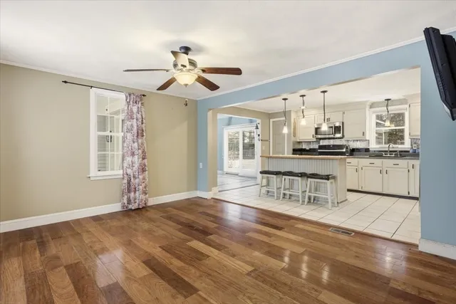 a kitchen with stainless steel appliances granite countertop a stove top oven a sink dishwasher a dining table and chairs with wooden floor