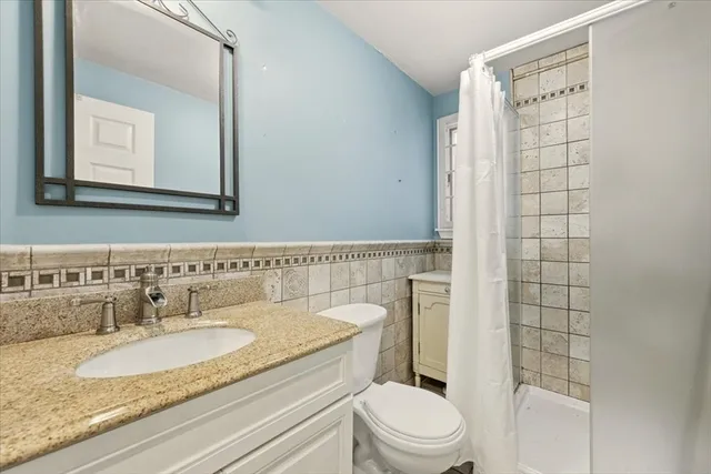 a bathroom with a granite countertop sink toilet a mirror and shower