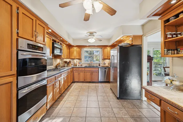 a kitchen with stainless steel appliances granite countertop a refrigerator a stove and a sink with cabinets
