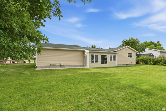 435 East 4th North Preston, ID 83263 - Photo 19 of 26 Expansive green lawn bordering a single-story residence with light-colored siding and a dark shingle roof