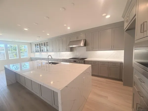 a large kitchen with kitchen island a sink a center island stainless steel appliances and a window