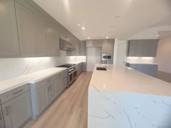 a large kitchen with a large counter top stainless steel appliances and cabinets