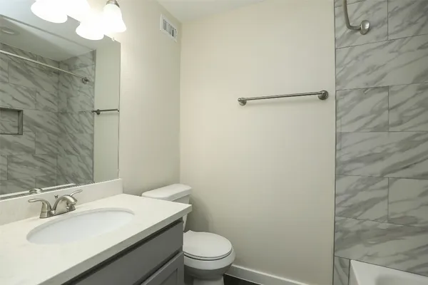 a bathroom with a granite countertop sink toilet a mirror and shower