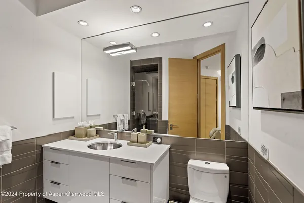 a bathroom with a sink vanity mirror and toilet
