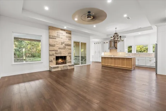 an empty room with wooden floor fireplace and windows