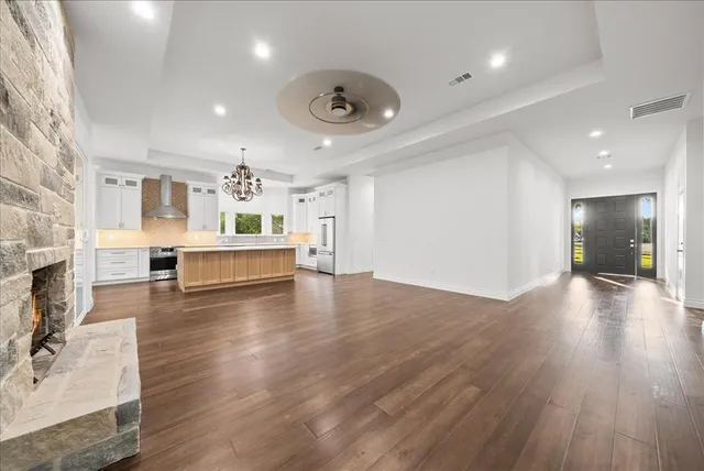 a view of a living room and kitchen with furniture wooden floor kitchen view and a fireplace