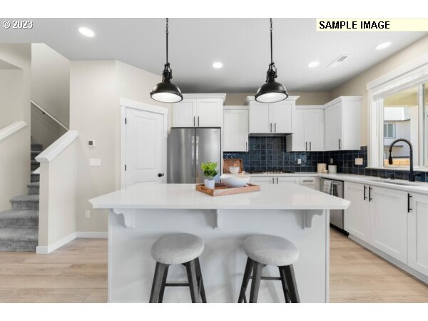 224 North 89th Loop, Unit 85 Ridgefield, WA 98642 - Photo 5 of 32 a kitchen with stainless steel appliances a dining table chairs and white cabinets
