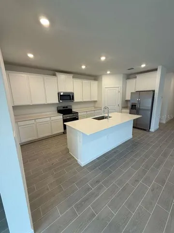 a large kitchen with kitchen island a stove a sink a refrigerator and cabinets