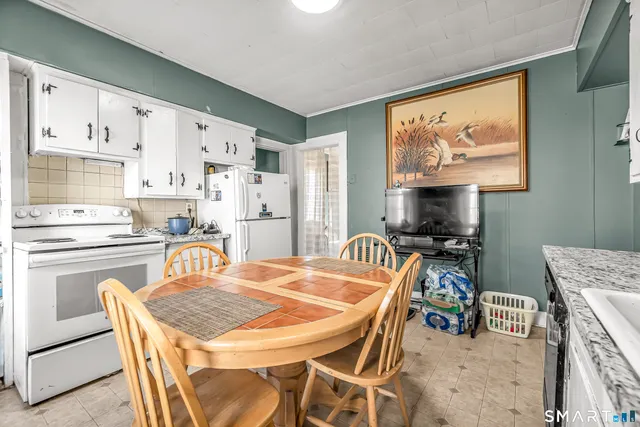 a kitchen with stainless steel appliances kitchen island granite countertop a dining table and chairs a refrigerator with wooden floors