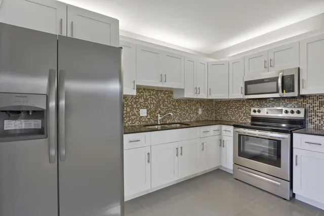 a kitchen with granite countertop a refrigerator stove and microwave