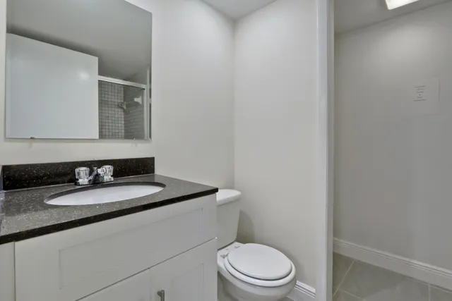 a bathroom with a granite countertop toilet sink mirror and vanity