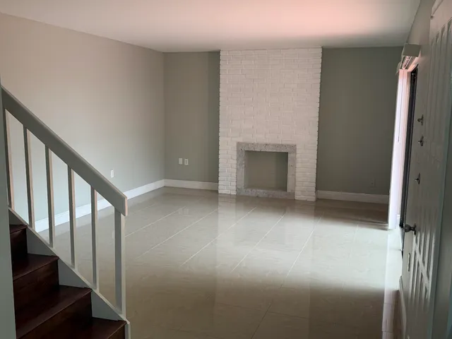 a view of an empty room with wooden floor and stairs