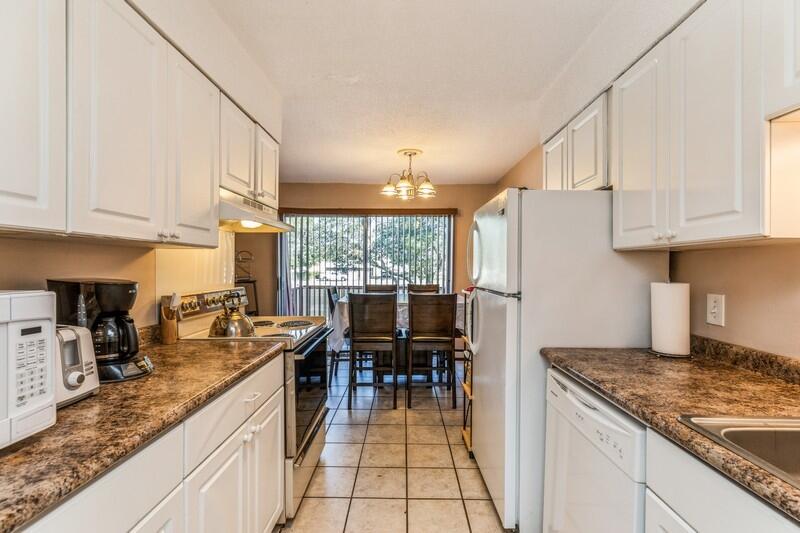 210 Pelham Road, Unit 201A Fort Walton Beach, FL 32547 - Photo 20 of 38 a kitchen with granite countertop a stove a sink a refrigerator and dining table