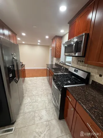 a kitchen with stainless steel appliances granite countertop a stove a sink and a refrigerator