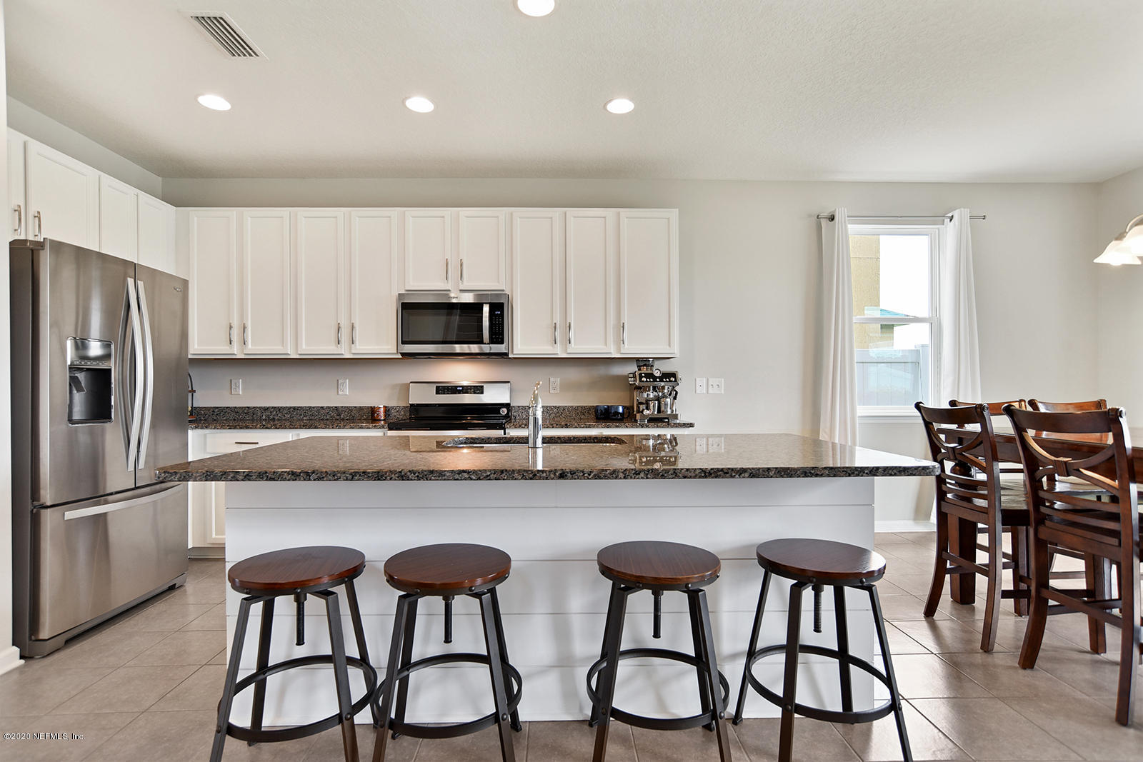 14780 Trellis Street Jacksonville, FL 32258 - Photo 12 of 29 a kitchen with stainless steel appliances granite countertop a table chairs refrigerator and microwave