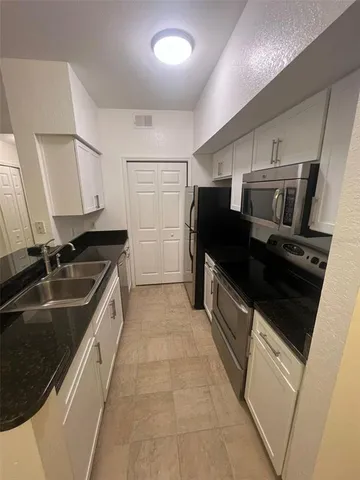 a kitchen with granite countertop a refrigerator and a sink