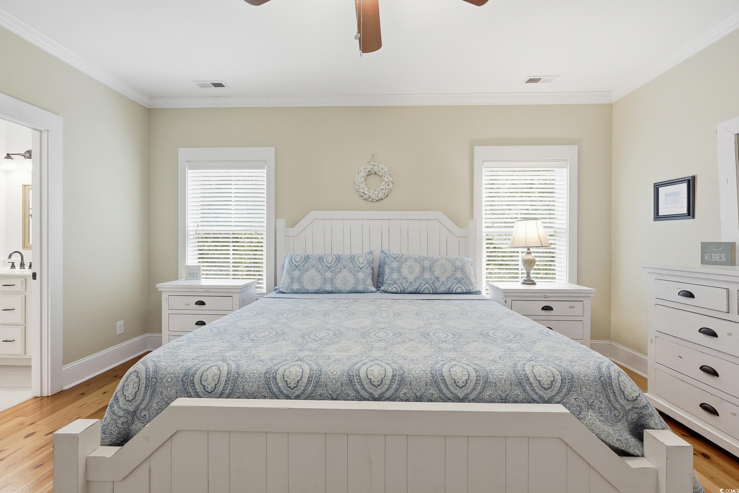 43 Sandlapper Way Pawleys Island, SC 29585 - Photo 13 of 33 Bedroom with light wood finished floors, ornamental molding, ensuite bathroom, and ceiling fan