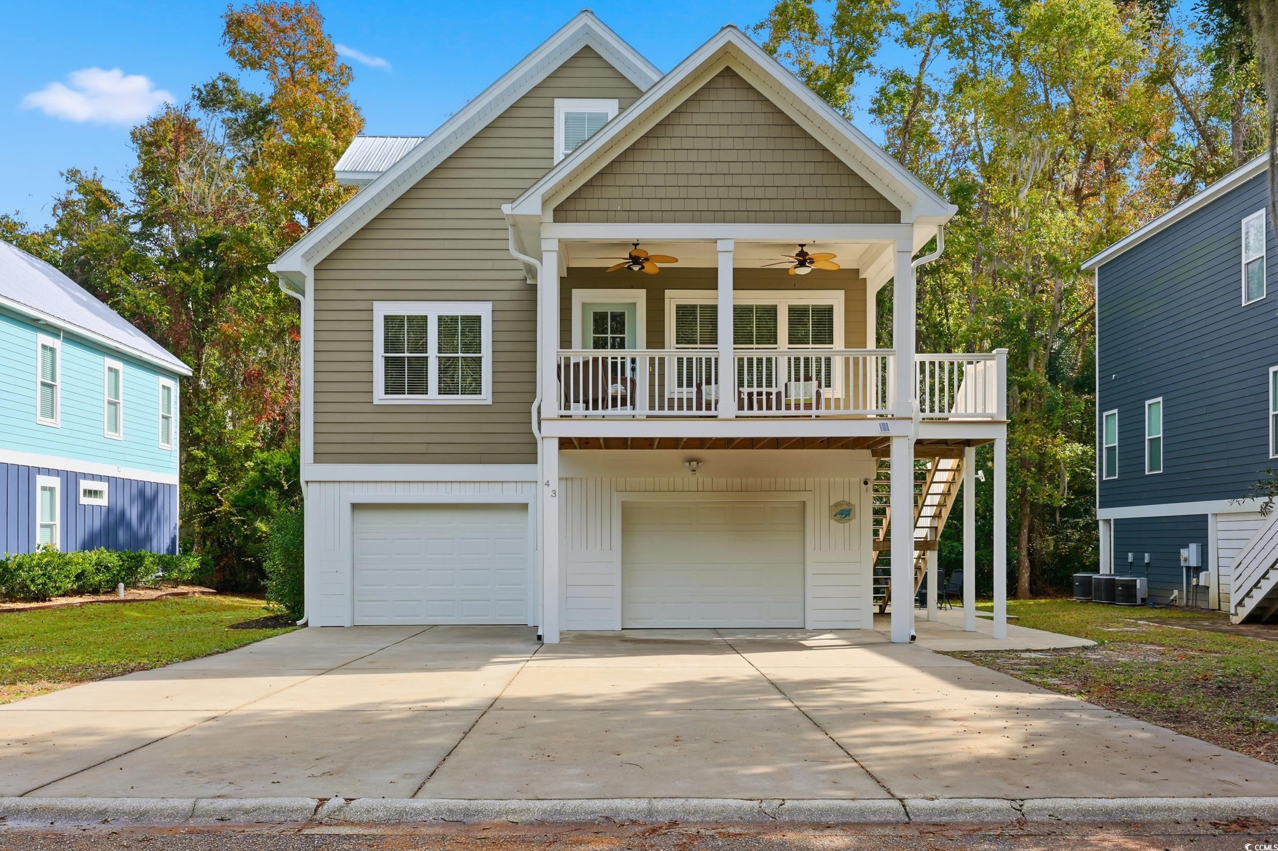 43 Sandlapper Way Pawleys Island, SC 29585 - Photo 3 of 33 Raised beach house with stairway, a ceiling fan, board and batten siding, a garage, and concrete driveway