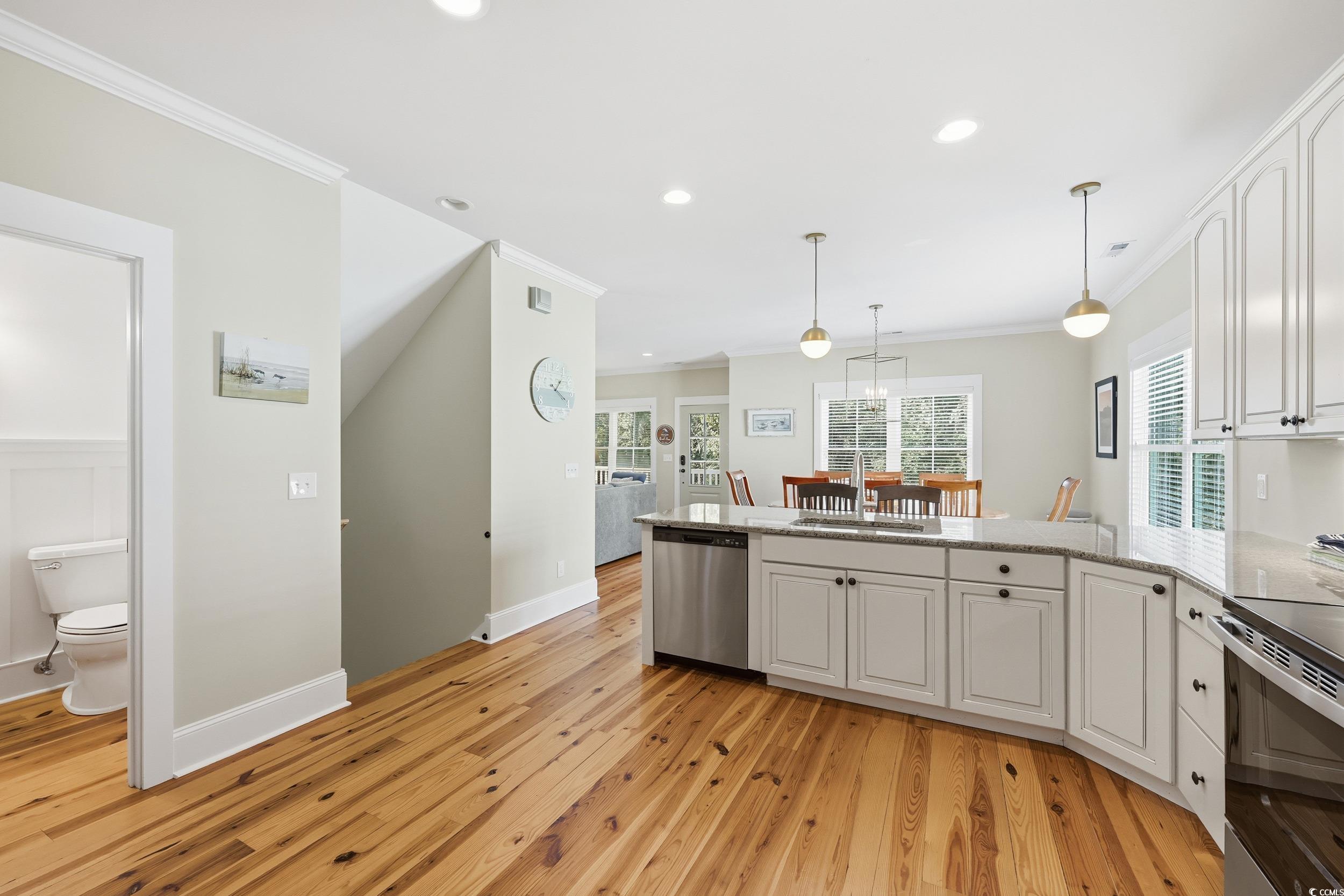 43 Sandlapper Way Pawleys Island, SC 29585 - Photo 9 of 33 Kitchen with crown molding, a peninsula, light stone counters, pendant lighting, and white cabinets