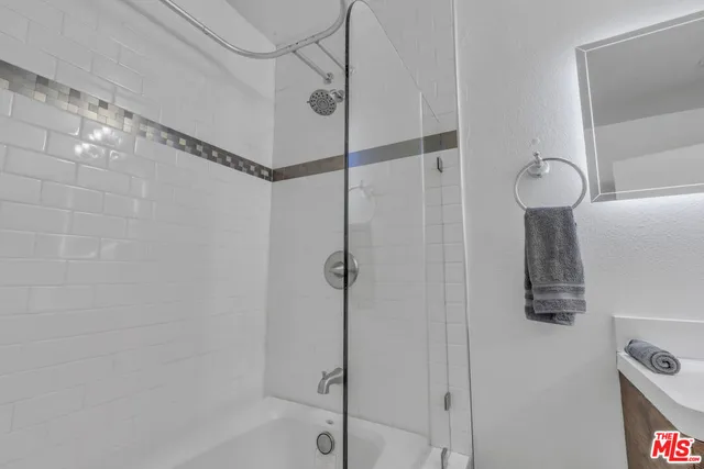 a bathroom with a tub shower vanity and a sink