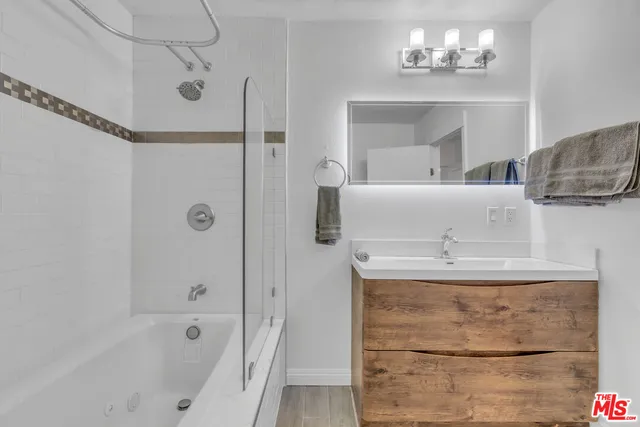 a kitchen with stainless steel appliances granite countertop a refrigerator a sink dishwasher a stove and a dining table with wooden floor