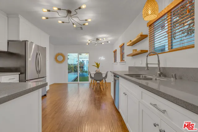 a kitchen with a refrigerator a sink dishwasher a stove and a dining table with wooden floor