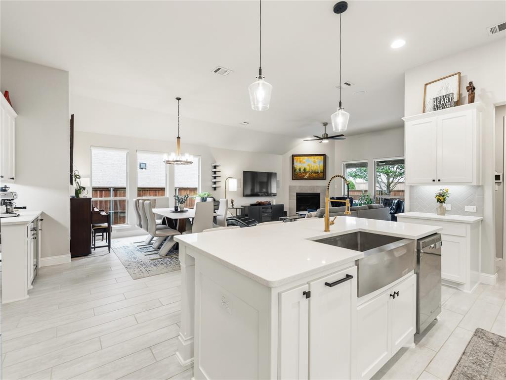 15340 Crape Myrtle Road Frisco, TX 75035 - Photo 12 of 40 Open-concept living area featuring a kitchen island with a stainless steel farmhouse sink, white cabinetry, light countertops, and wood-finish tile flooring