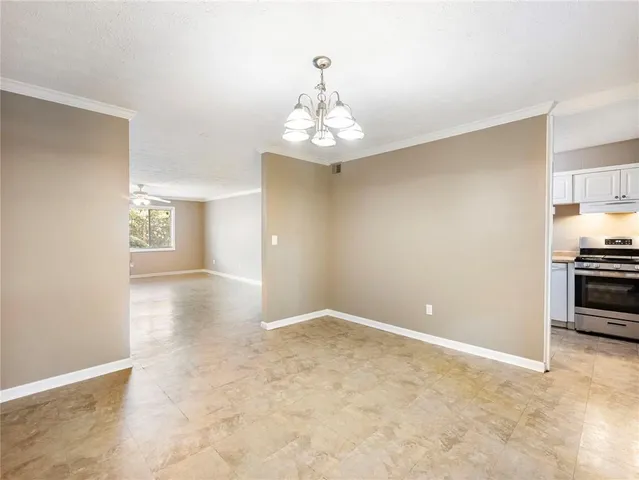 a view of an empty room with a chandelier fan