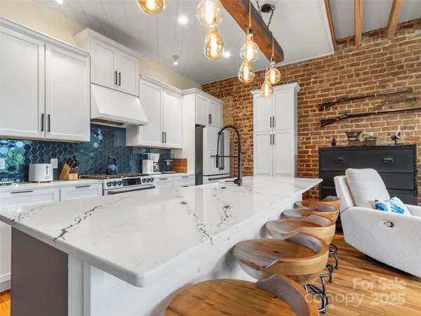 a kitchen with stainless steel appliances kitchen island granite countertop a stove a sink a dining table and chairs with wooden floor