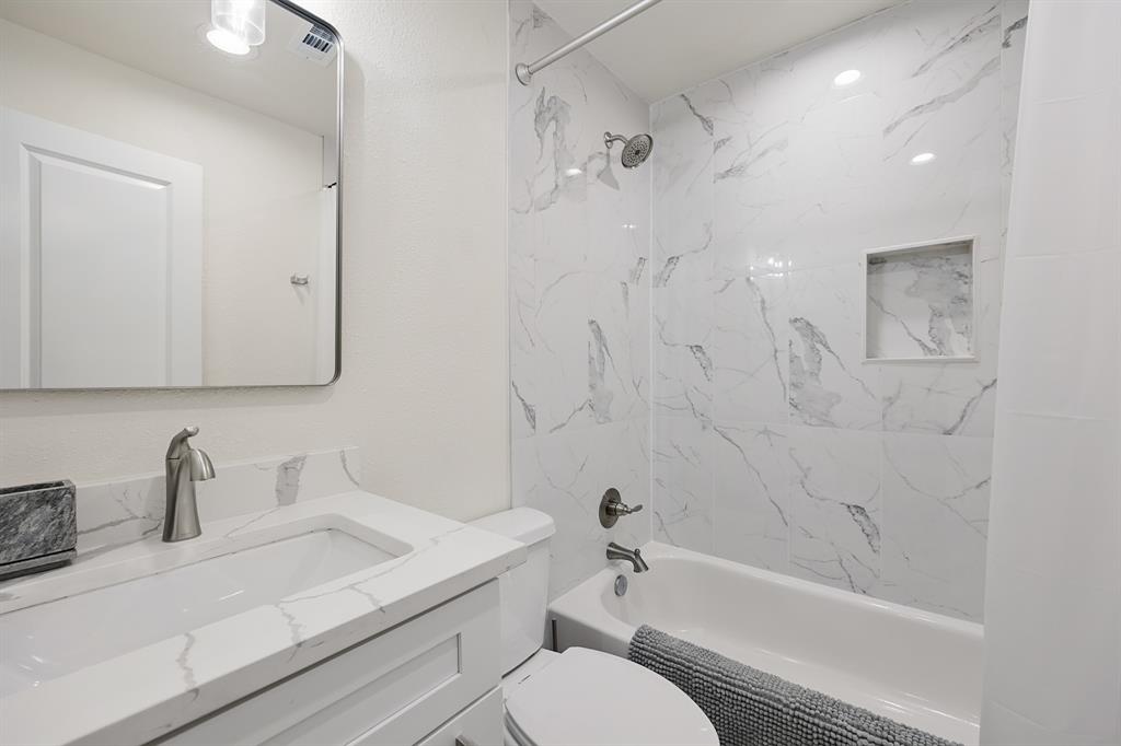 114 Ricky Road Gun Barrel City, TX 75156 - Photo 15 of 18 Bathroom featuring a white vanity with an integrated sink and brushed nickel faucet, a rounded rectangular mirror, and a built-in shower niche