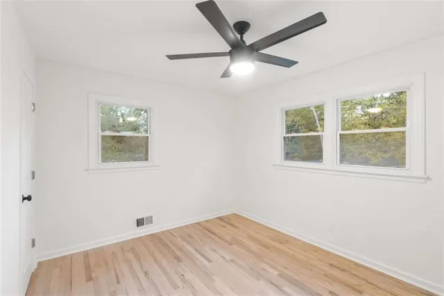 an empty room with wooden floor and ceiling fan