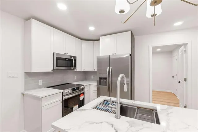 a kitchen with stainless steel appliances kitchen island granite countertop a refrigerator a sink a stove and oven