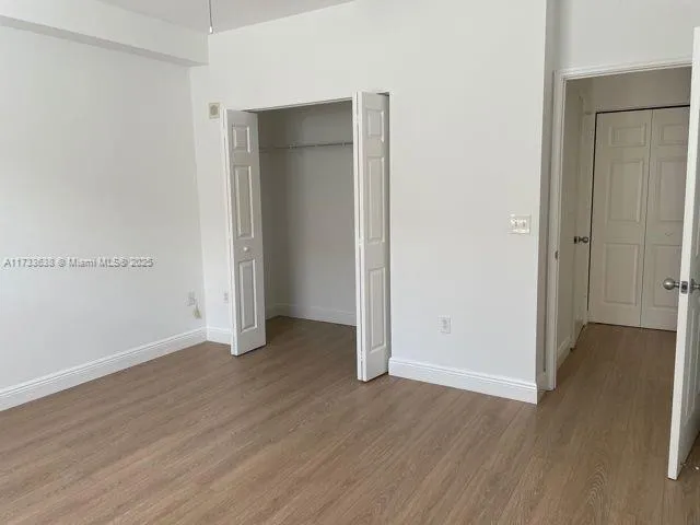 an empty room with wooden floor & closet area