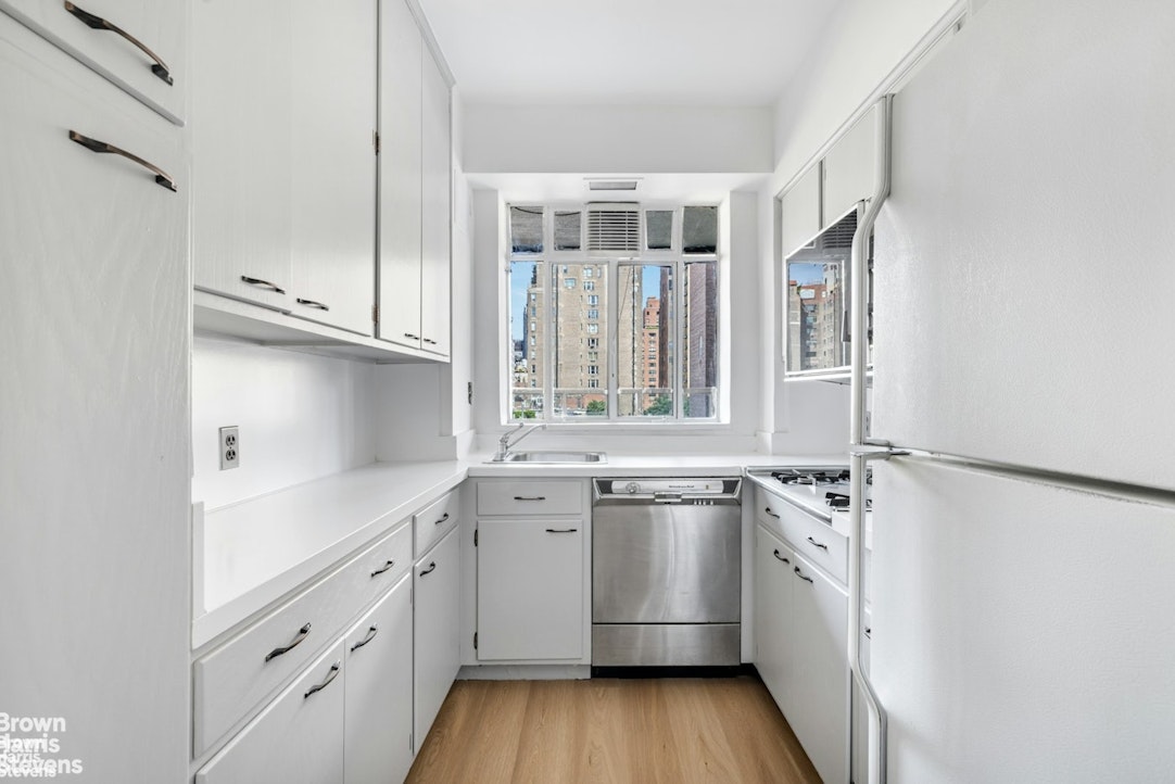 20 East 74th Street, Unit 8A Manhattan, NY 10021 - Photo 6 of 22 a kitchen with stainless steel appliances granite countertop a sink and wooden cabinets