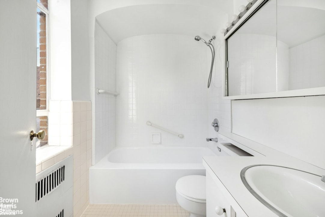 20 East 74th Street, Unit 8A Manhattan, NY 10021 - Photo 7 of 22 a bathroom with a granite countertop bathtub shower sink vanity mirror and toilet