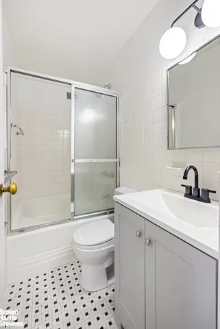 a bathroom with a granite countertop bathtub shower sink vanity mirror and toilet