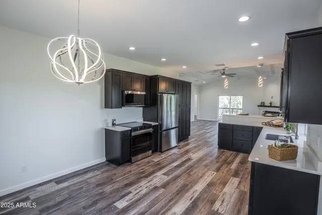 a large kitchen with a wooden floor and stainless steel appliances