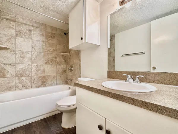 a bathroom with a granite countertop sink toilet a mirror and bathtub