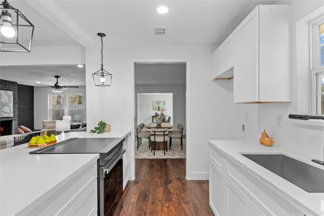 a kitchen that has a lot of cabinets a sink and wooden floor