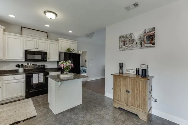 a kitchen with kitchen island granite countertop a sink appliances cabinets and furniture