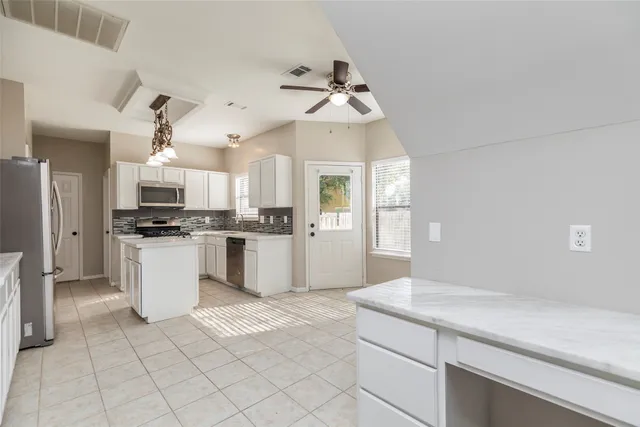 a kitchen with a refrigerator and white cabinets