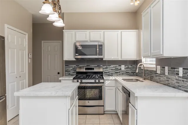 a kitchen with a sink a stove a chandelier and cabinets