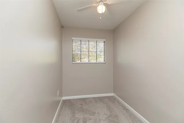 an empty room with a window and a ceiling fan