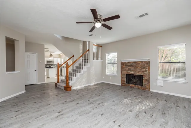 a view of an empty room with wooden floor a fireplace and a window