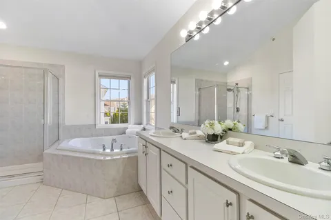 a bathroom with a tub a double vanity sink a window and a mirror