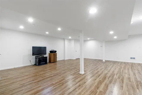 an empty room with wooden floor and a flat screen tv