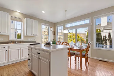 a kitchen with stainless steel appliances granite countertop a stove a refrigerator a sink and white cabinets with wooden floor